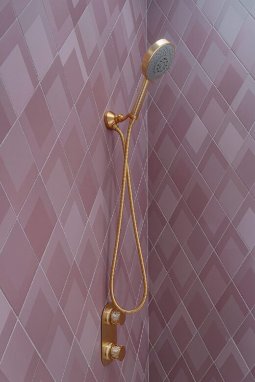 Pink geometric wall tiles in girls bathroom remodel, gold fixtures